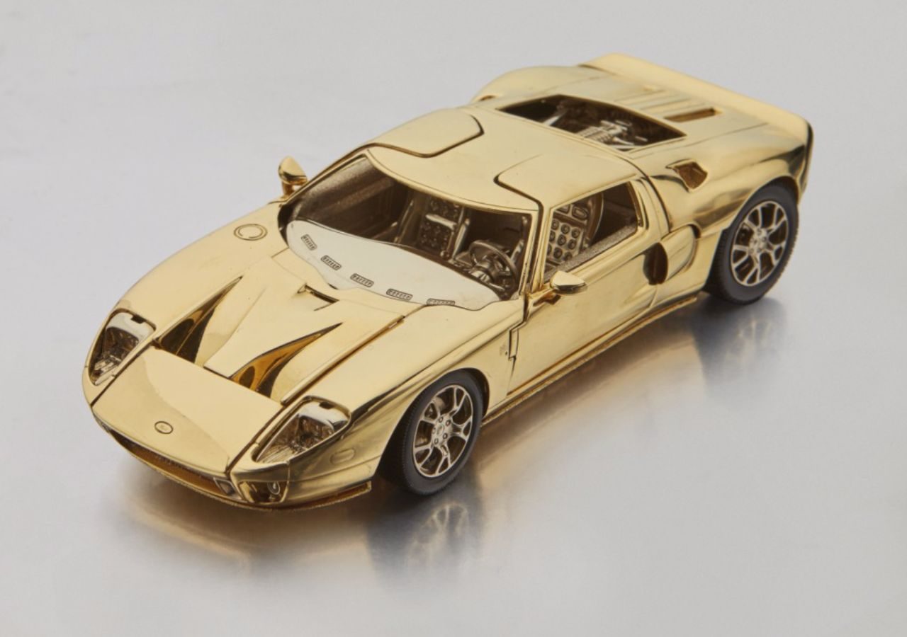 Een gouden model van een Ford GT-sportwagen op een witte ondergrond.