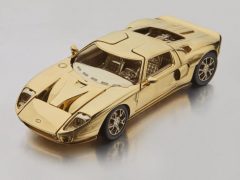 Een gouden model van een Ford GT-sportwagen op een witte ondergrond.