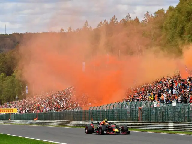 Een Formule 1 Red Bull-raceauto die met oranje rook over het circuit van Zandvoort rijdt.