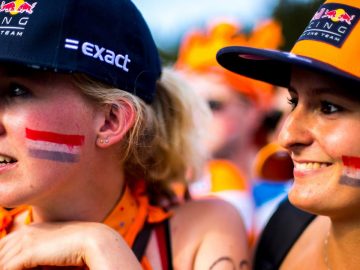 Twee vrouwen met Formule 1 op Zandvoort-hoeden op hun gezicht geschilderd.