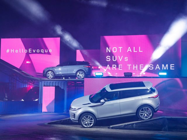 De Range Rover Evoque staat geparkeerd voor een neonbord.
