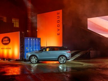 De Range Rover Evoque staat geparkeerd voor een verlicht gebouw.