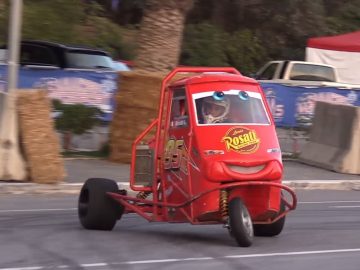 Een rode Piaggio die door de straat rijdt.