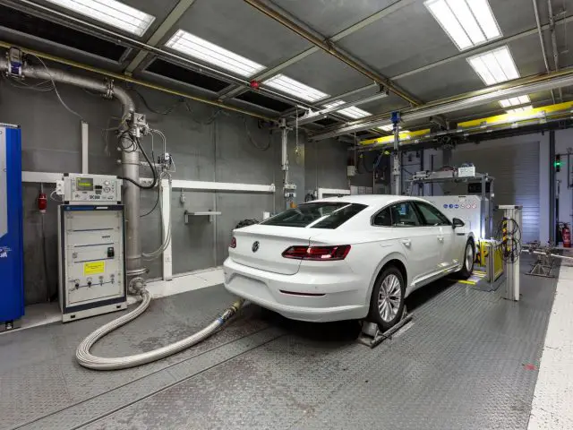 Een witte auto wordt in een garage gereinigd volgens de WLTP-normen.