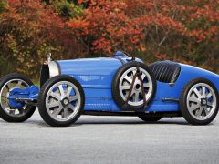 Een blauwe vintage Bugatti-raceauto staat geparkeerd op een weg.
