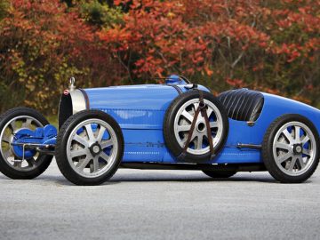 Een blauwe vintage Bugatti-raceauto staat geparkeerd op een weg.