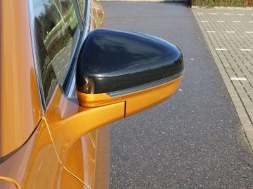 Een oranje DS 7 Crossback met een zwarte zijspiegel.