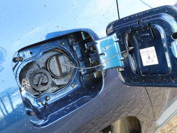 Een close-up van een blauwe Dacia Duster met een brandstofpomp.