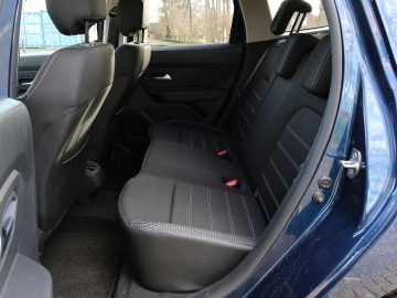De achterbank van een blauwe Dacia Duster met zwarte stoelen.