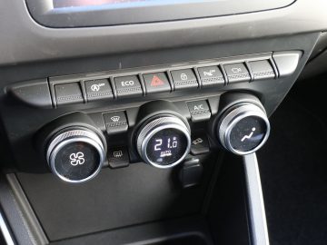 Het dashboard van een Dacia Duster met verschillende knoppen en meters.