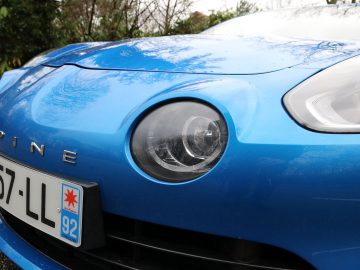 De voorkant van een blauwe Alpine A110-sportwagen.