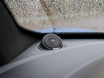 Een Alpine A110-luidspreker in een auto met regendruppels erop.