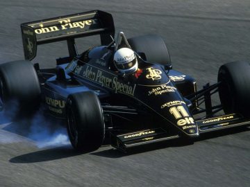 Een zwarte raceauto met een vleugel en rook die eruit komt.