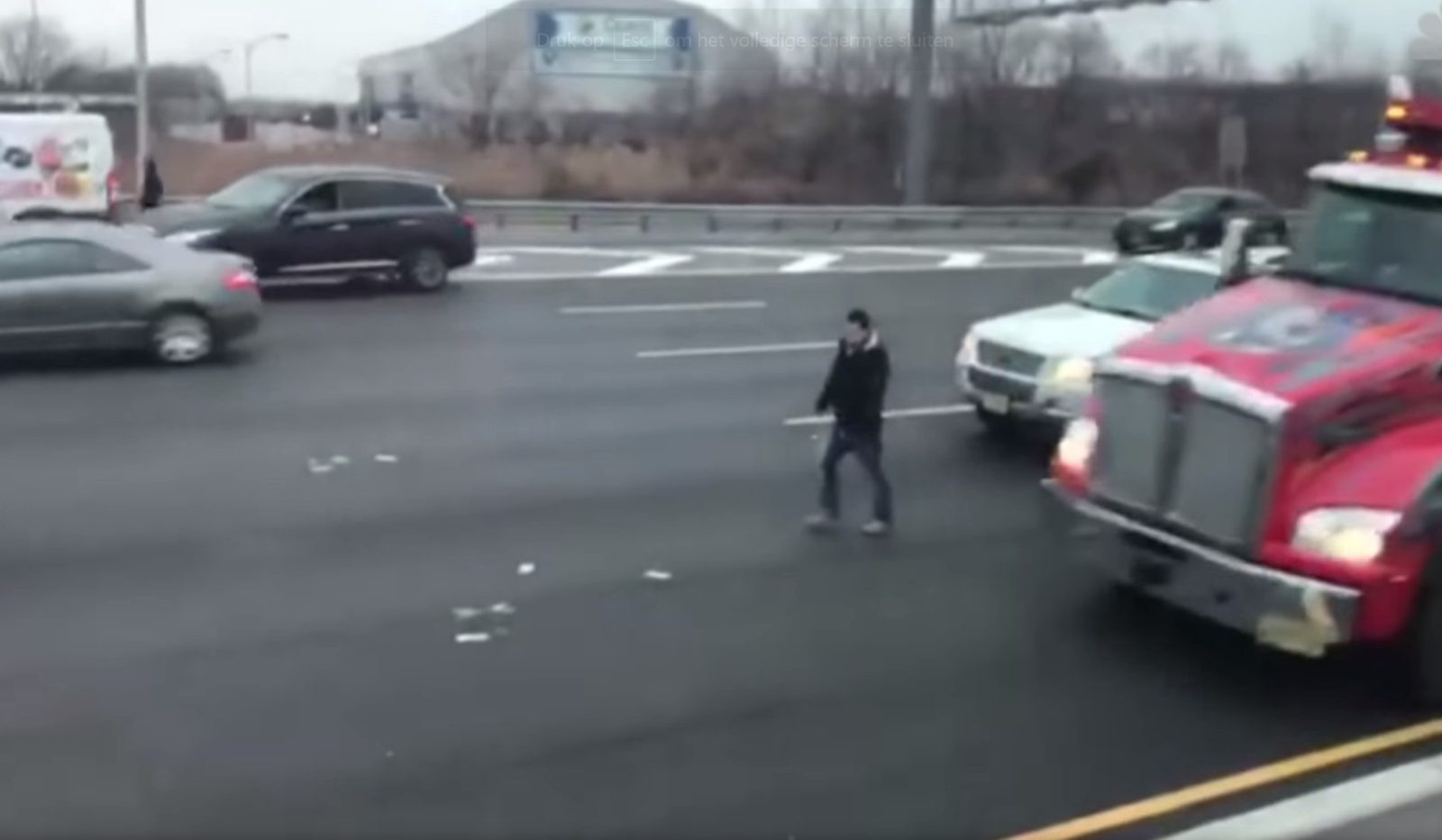 Een man staat naast een semi-vrachtwagen op de Amerikaanse snelweg waar geld ligt voor het oprapen.