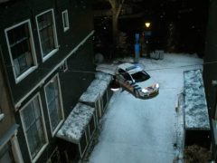 Een auto die 's nachts door een besneeuwde straat rijdt, vlakbij Sint.