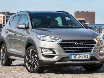 De Hyundai Tucson uit 2019 staat geparkeerd op een geplaveide straat.