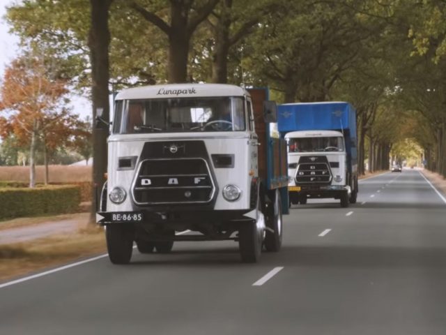 Twee vrachtwagens, waaronder de oudste DAF-truck, rijden over een weg in een bosrijke omgeving.