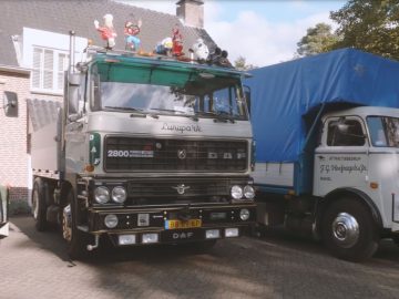 Voor een huis stond een groep vrachtwagens, waaronder de oudste DAF-truck, geparkeerd.
