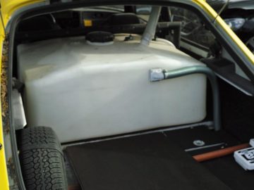 De kofferbak van een gele auto met daarin een watertank van een wrijvingsmeter.