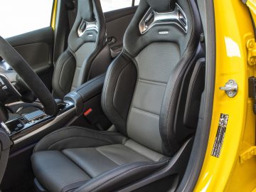 Het interieur van een gele AMG-sportwagen met zwarte stoelen.