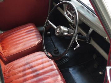 Het interieur van een oude auto met leren stoelen en een stuur met Phil Collins-thema.