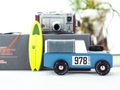 Een Candylab blauwe speelgoedauto met een surfplank en een camera.