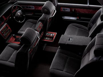 Het interieur van een auto met zwartleren stoelen en een rood stuur roept de luxe van de eeuw op.