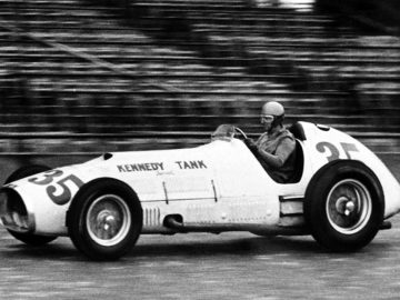 Een zwart-witfoto van een man die in een Indy-raceauto rijdt.