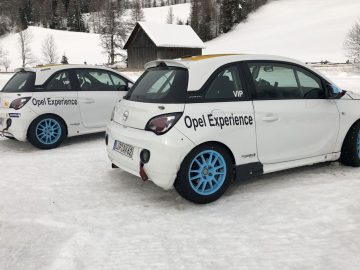 Twee witte Adam R2-auto's geparkeerd in de sneeuw naast elkaar.