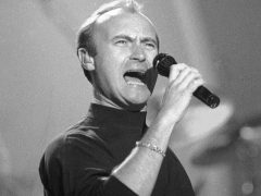 Phil Collins zingt in een microfoon.