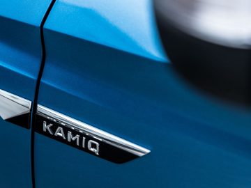 Een close-up van de badge op een blauwe Kamiq-auto.