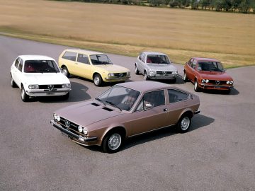 Een groep Alfa Romeo-auto's geparkeerd in een veld.