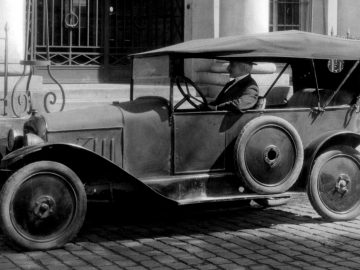 Een oude zwart-witfoto van een man die in een Citroën rijdt.