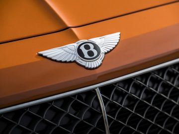 Een Bentley Bentayga Speed-badge op de motorkap van een oranje auto.
