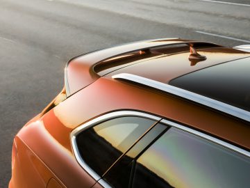 Het achteraanzicht van een oranje Bentley Bentayga Speed met dakspoiler.