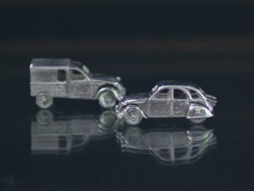 Een paar zilveren Tres Precieux Voitures oorknopjes in de vorm van een auto.
