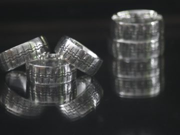 Een set zilveren ringen op een zwarte Tres Precieux ondergrond.