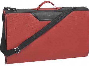 Een rode kofferset met een zwarte draagband.