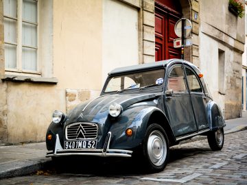 Een oude Franse auto geparkeerd op een geplaveide straat.