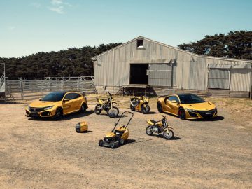 Een groep gele Honda-voertuigen geparkeerd voor een schuur.