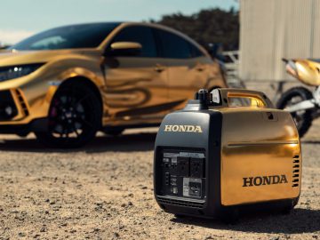 Een gouden Honda-generator staat naast een gouden auto.