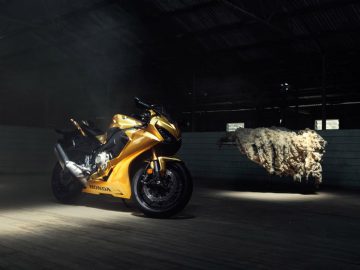 Een gouden Honda-motorfiets geparkeerd in een donkere kamer.