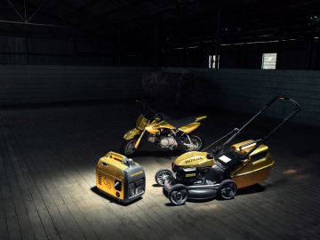 Een gele Honda-grasmaaier en een motorfiets in een magazijn.
