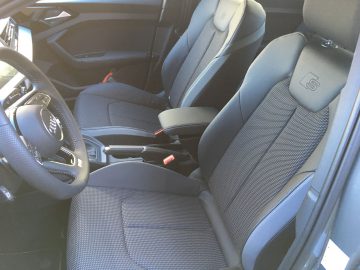 Het interieur van een Audi A1 met zwarte stoelen en stuur.