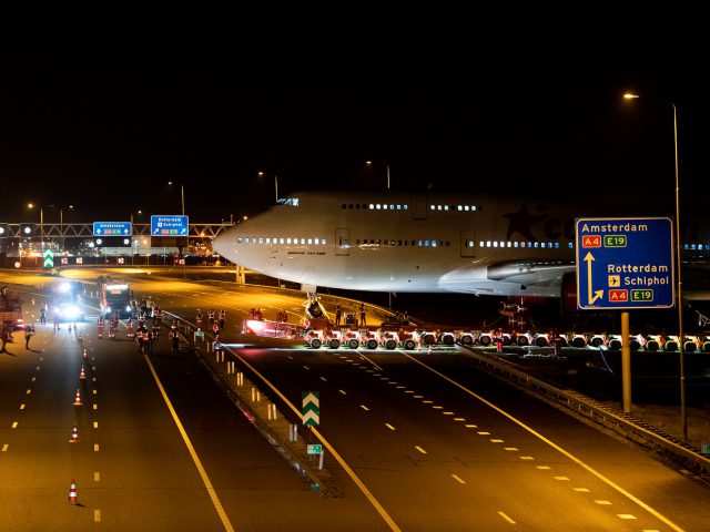 Een wit Boeing 747-vliegtuig op een landingsbaan 's nachts.