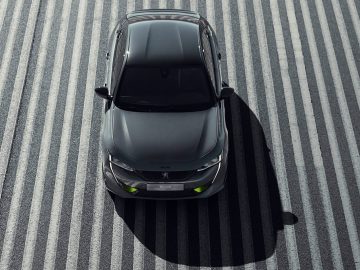 Een luchtfoto van een zwarte 508 Peugeot op een gestreept oppervlak.