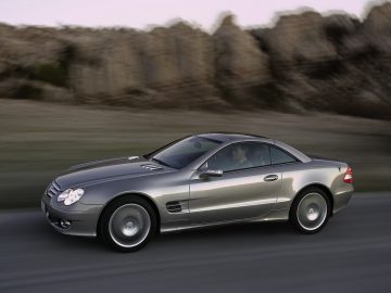 De zilveren Mercedes-Benz SL rijdt over de weg.