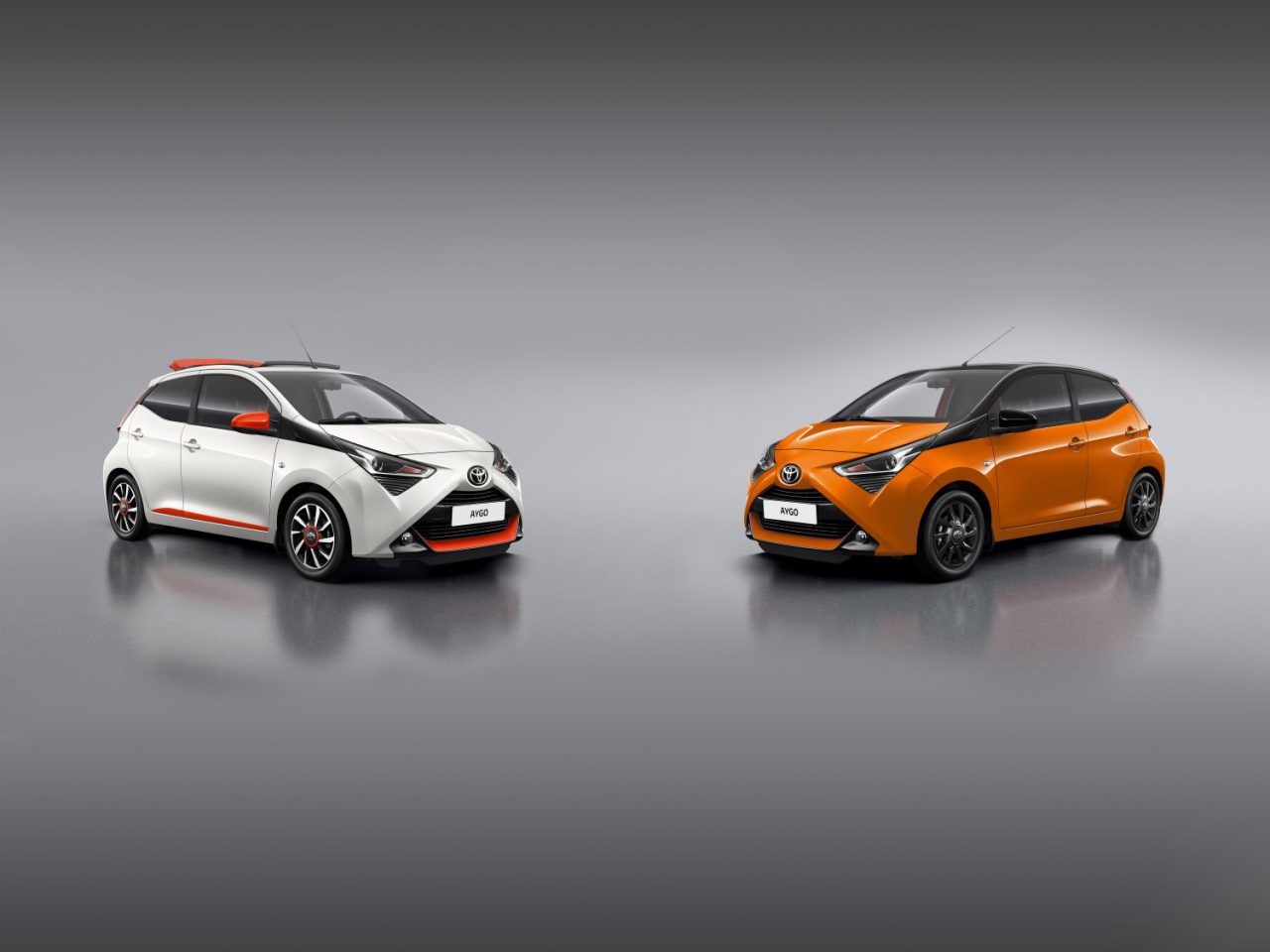 Twee Aygo-auto's op een grijze achtergrond.