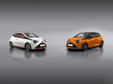Twee Aygo-auto's op een grijze achtergrond.