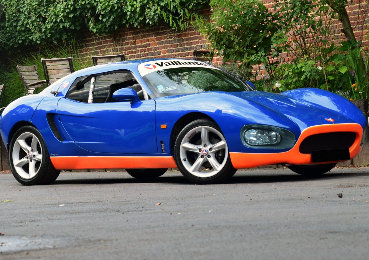Een blauw-oranje Vaillant-sportwagen geparkeerd aan de kant van de weg.